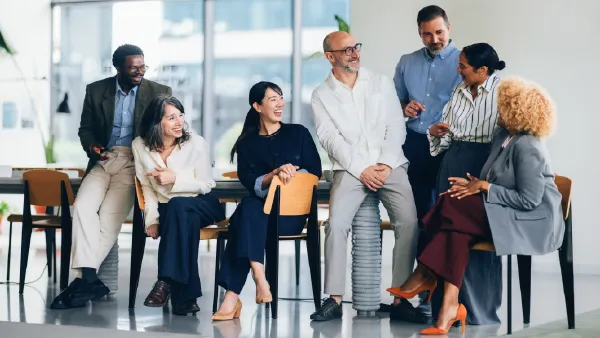Seven business people in a lobby sitting at a table having a cheerful discussion