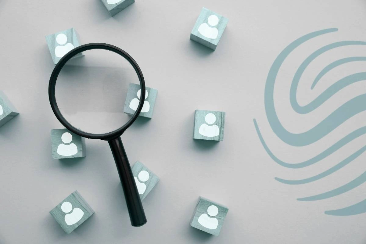 A magnifying glass above scattered blocks with icons of people on them