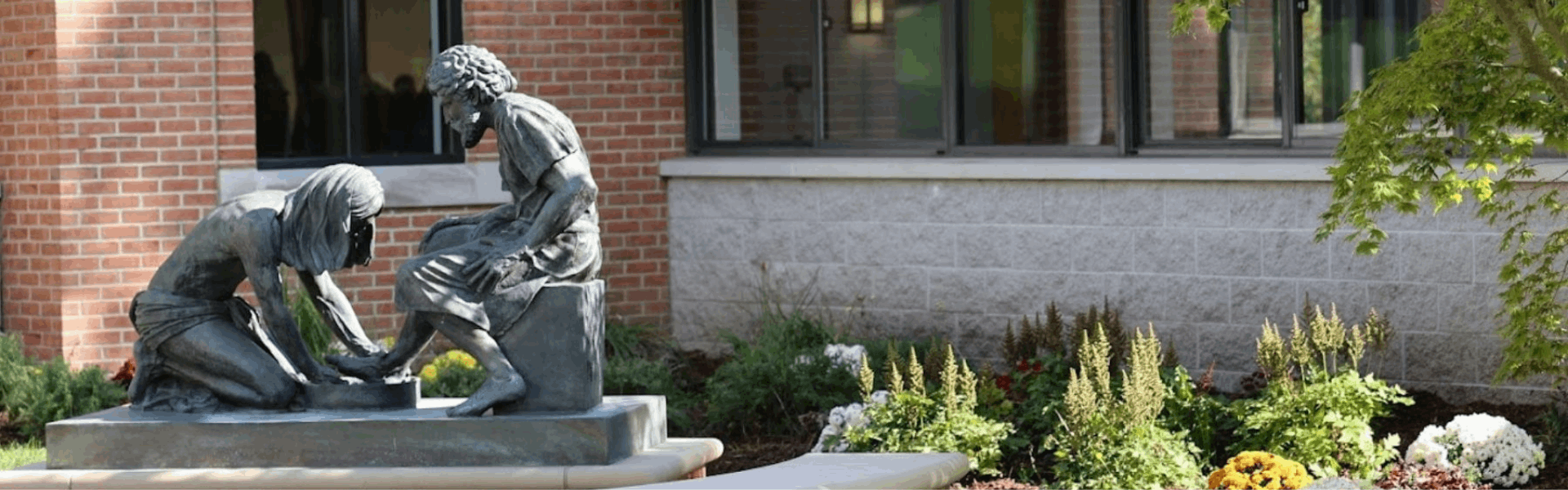 Exterior image of Kuyper College campus featuring a sculpture of Jesus washing another's feet